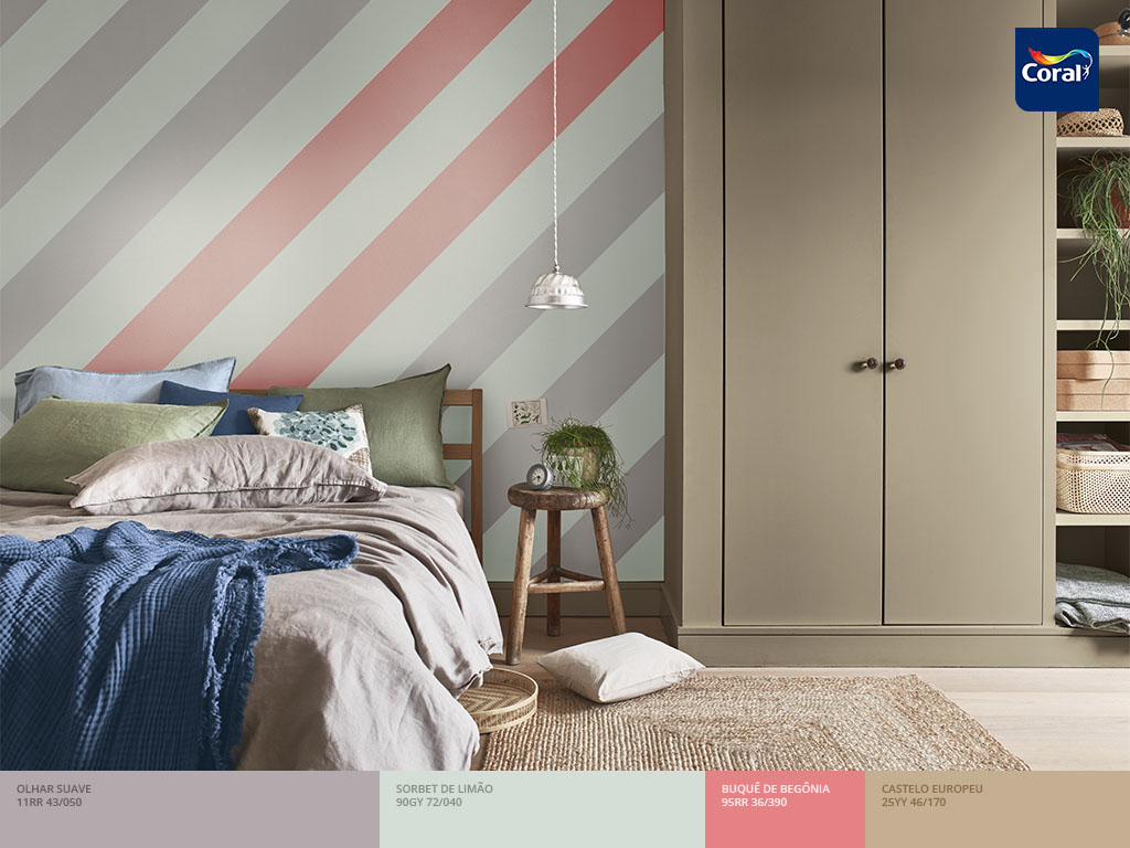 A parede listrada em diagonal é uma escolha estratégica para decorar o quarto de casal. Imagem: Coral Matiz