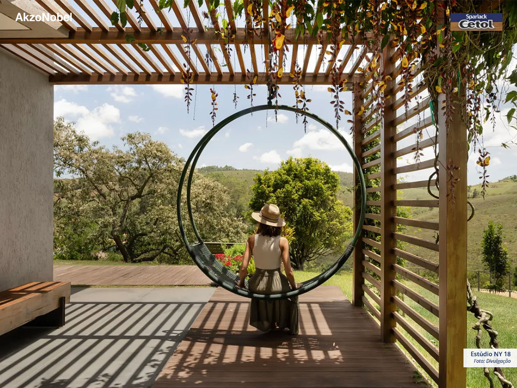 O pergolado de madeira com plantas cria um ambiente natural com sombra fresca.